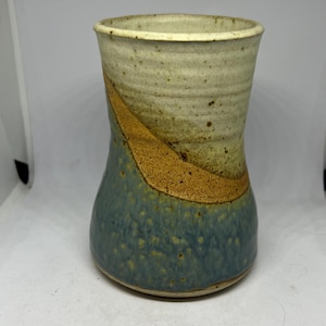 May include: A ceramic vase with a blue, brown, and white glaze. The vase has a wide mouth and a narrow base.