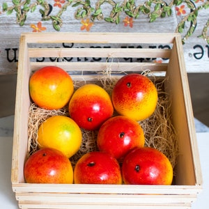 May include: A wooden crate filled with eight red and yellow fruit. The fruit is arranged in a single layer, with some fruit overlapping.