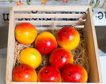 May include: A wooden crate filled with eight red and yellow fruit. The fruit is arranged in a single layer, with some fruit overlapping.