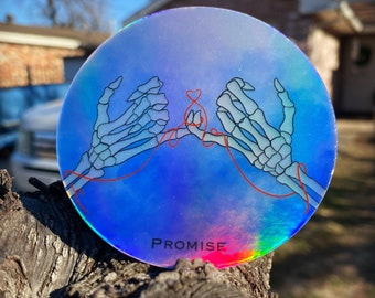 May include: A holographic sticker with a blue, purple, and pink iridescent background. Two skeleton hands are holding a red string tied in a heart shape. The text "PROMISE" is printed in black at the bottom.