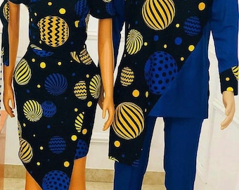 Op de afbeelding: Een bijpassende outfitset voor koppels met een zwarte en blauwe geprinte jurk en een lang mouw shirt met bijpassende broek. Het patroon bevat gele en blauwe cirkels op een zwarte achtergrond.