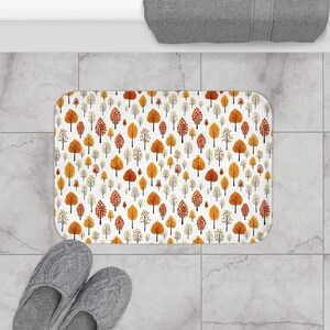 May include: White bath mat with a repeating pattern of orange and yellow trees. The trees are stylized and have a simple design.