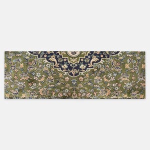 May include: A rectangular green rug with an intricate floral pattern. The rug features a central medallion design in navy blue and cream, surrounded by detailed floral motifs in shades of green, cream, and peach. The rug's edges are finished with a detailed border.