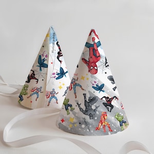 Puede incluir: Dos gorros de fiesta con ilustraciones de superhéroes. Los gorros en forma de cono tienen fondos blancos y grises. Los gorros presentan imágenes de Spider-Man, Capitán América, Hulk y otros personajes. Se adjuntan cintas blancas.