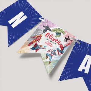Può includere: Uno striscione blu e bianco con uno sfondo ad acquerello che presenta diversi supereroi, tra cui Iron Man, Capitan America, Thor, Hulk, Spiderman e Pantera Nera. Lo striscione dice "Oliver compie 5 anni Buon compleanno!"