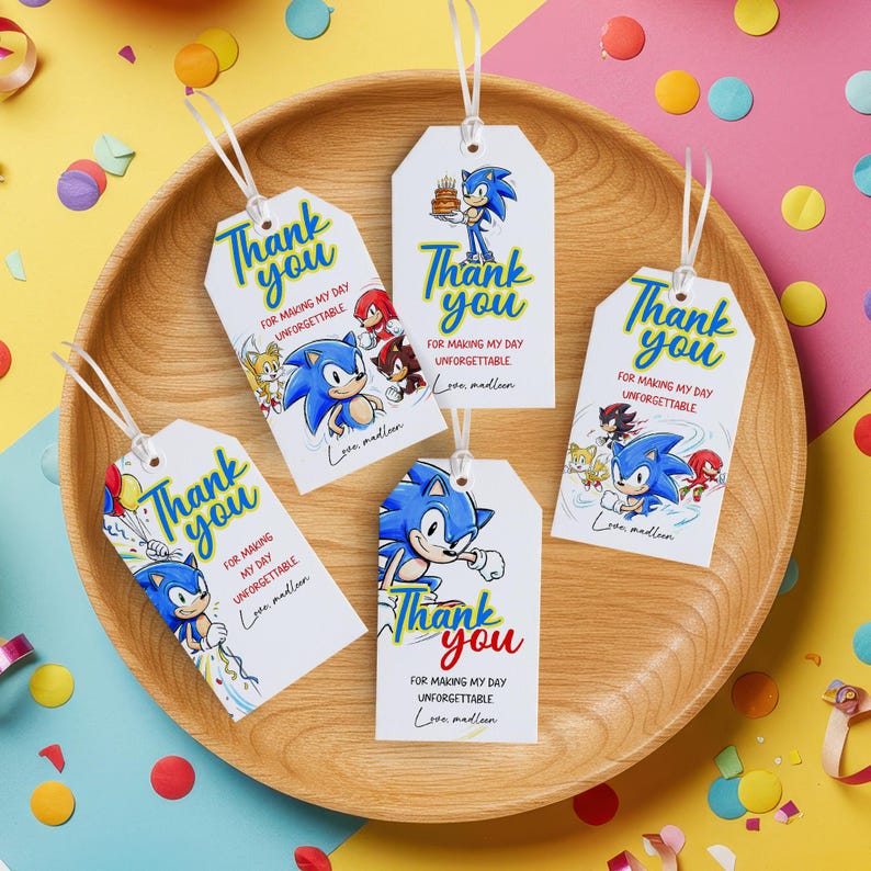 May include: White gift tags with the text "Thank you" in blue and red, featuring the character Sonic the Hedgehog. The tags have a white ribbon and are arranged on a wooden tray. The tags also include the text "For making my day unforgettable."