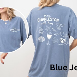 May include: A blue jean colored t-shirt featuring white screen-printed graphics. The front displays the text 'from CHARLESTON with love'. The back features the same text above illustrations of a bikini, starfish, whale tail, wine glass, seagulls, sandals, sun hat, seashell, and coral, with 'olivia's bachelorette august 2025' printed below.