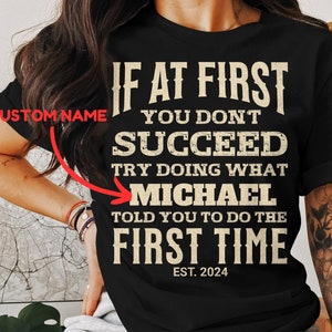 May include: Black t-shirt with a vintage-style graphic that reads "If at first you don't succeed, try doing what [CUSTOM NAME] told you to do the first time. Est. 2024".