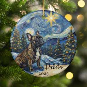 May include: Round ceramic Christmas ornament featuring a brindle French Bulldog in a Van Gogh-style starry night scene. The ornament has a gold string for hanging, with the name "Dakota" and the year "2025" printed on it.