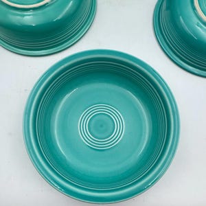 Op de afbeelding: Een set van drie ronde turquoise kommen met een glanzende afwerking en concentrische ringpatronen op de binnenkant van de bodem en de buitenkant. Elke kom heeft een brede rand en een egale kleur over het gehele keramische oppervlak.