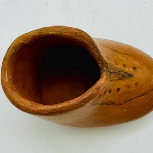 May include: A small, brown, ceramic shoe-shaped planter with a rough, textured surface.