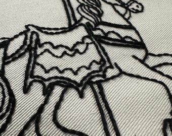 May include: Black thread embroidery of a carousel horse on a white fabric stretched within a wooden hoop. The horse has a flowing mane and is adorned with decorative elements. The embroidery is detailed and the stitches are visible.