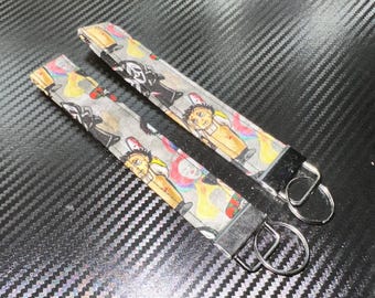 May include: Two fabric wristlet keychains featuring a repeating pattern of horror movie characters on a light gray background. Each keychain has a silver-toned metal clamp at one end with an attached circular metal split ring for holding keys.