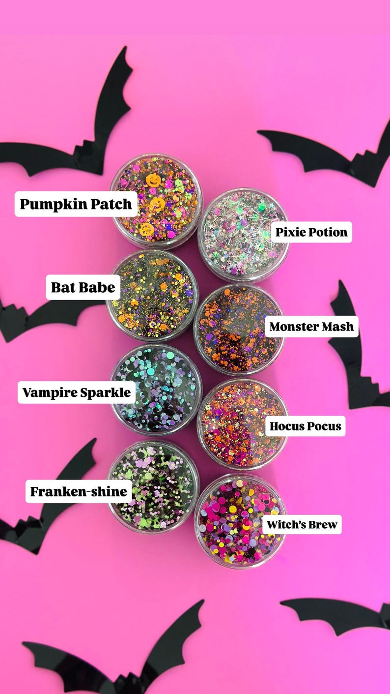May include: A collection of eight small, clear containers filled with colorful glitter mixes, each labeled with a Halloween-themed name like "Pumpkin Patch" and "Witch's Brew." Black bat silhouettes decorate the bright pink background.