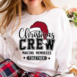 May include: White sweatshirt with a red and white Santa hat graphic and the text "Christmas Crew Making Memories Together".