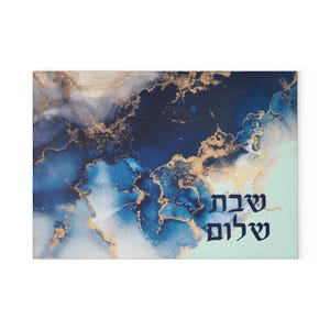 May include: Rectangular decorative art piece with a blue, gold, and white abstract design. The artwork features the Hebrew text "Shabbat Shalom" in dark blue. The background has a marbled effect.