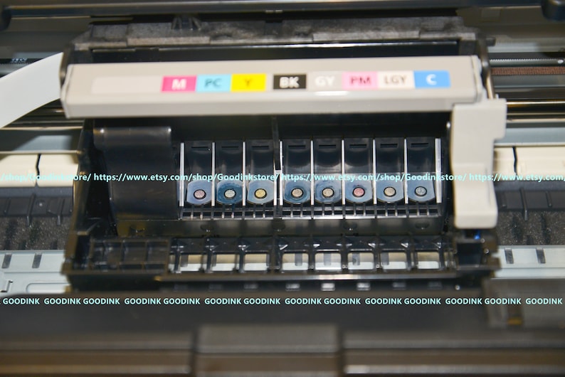 May include: Close-up of a printer ink cartridge tray with eight ink cartridges. The cartridges are labeled with the colors: magenta, photo cyan, yellow, black, gray, photo magenta, light gray, and cyan.