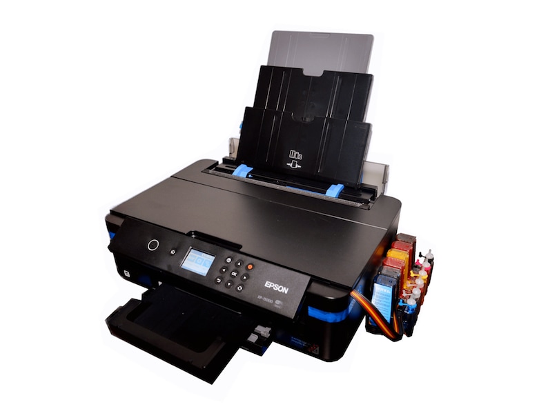 K&ouml;nnte beinhalten: Ein schwarzer Epson-Drucker mit ausgezogenem Papierfach. Der Drucker hat ein Bedienfeld mit Tasten und einem kleinen Bildschirm. Tintenpatronen sind an der Seite sichtbar. Der Drucker steht vor wei&szlig;em Hintergrund.