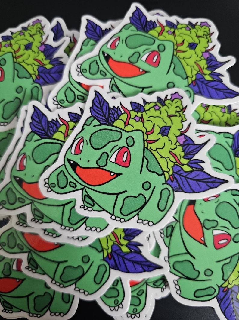 May include: A collection of stickers featuring a green cartoon character with red eyes and a smiling red mouth. The character has a green bulbous growth on its back with purple and green accents. The stickers are on a black background.
