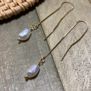 May include: A pair of gold chain earrings with a white pearl pendant on each chain.