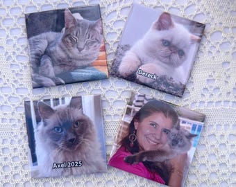 May include: Four square magnets featuring cat portraits. One magnet shows a gray tabby cat, another a white cat with blue eyes, and a third a fluffy cat with blue eyes and the text "Axel 2025". The fourth magnet shows a woman holding a cat.