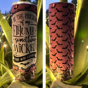 May include: A pink and black tumbler with a glittery finish. The tumbler features a white graphic with the text "By the pricking of my thumb, something wicked this way comes." and a black bat silhouette.