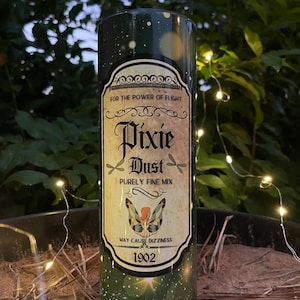 Puede incluir: Un vaso verde y dorado con una etiqueta que dice "Pixie Dust Purely Fine Mix" y una ilustración de un hada. La etiqueta también incluye el texto "For the power of flight" y "May cause dizziness". El año 1902 está impreso en la etiqueta.