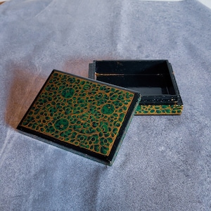 May include: An open wooden box with a green and gold floral design on the lid. The box is empty and the lid is open.