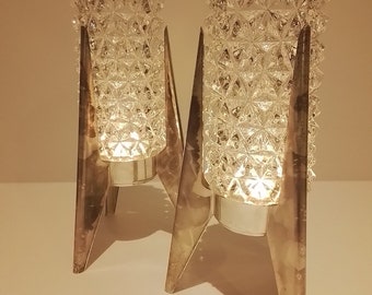 Puede incluir: Dos candelabros de plata con candelabros de vidrio transparente con un patrón geométrico. Los candelabros tienen un diseño de cohete.