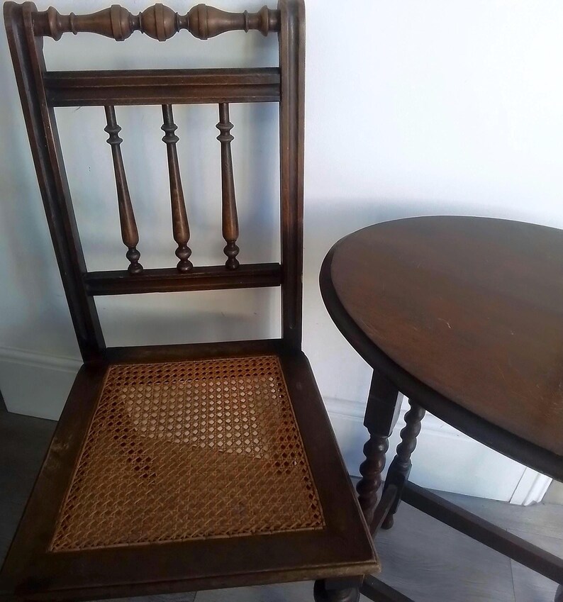 Puede incluir: Una silla de madera marr&oacute;n oscuro con un asiento de mimbre tejido y una mesa de madera marr&oacute;n oscuro a juego con una tapa redonda.