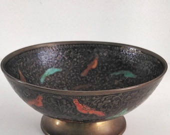 May include: A black metal bowl with a decorative design of birds and floral patterns. The bowl has a wide rim and a round base.