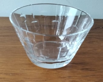 May include: A clear glass tumbler with a geometric pattern. The glass is empty and sitting on a wooden surface.