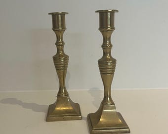May include: A pair of antique brass candlesticks with a fluted design on the body and a square base.