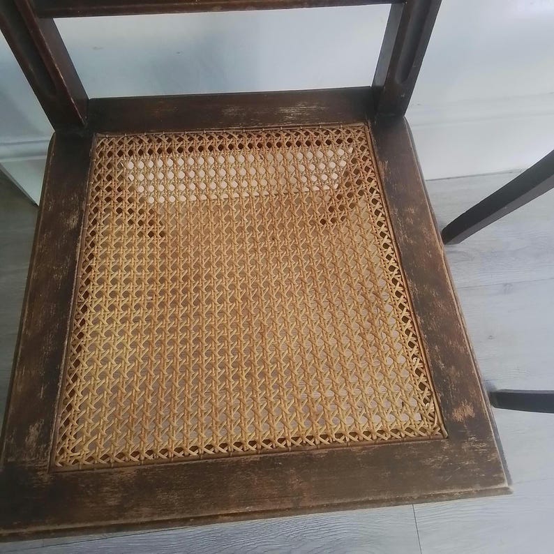 Puede incluir: Una silla de madera con un asiento de mimbre tejido. La silla tiene un acabado marr&oacute;n oscuro y est&aacute; en buen estado.
