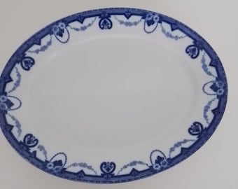 May include: A white oval serving platter with a blue and white floral design around the edge.