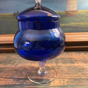 May include: A cobalt blue glass jar with a clear glass lid and a twisted clear glass pedestal base.