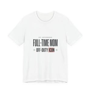 May include: White t-shirt with the text "EST. MOTHERHOOD FULL-TIME MOM OFF-DUTY ICON" in black and pink. The shirt has a crew neck and short sleeves. A casual, everyday wear tee.