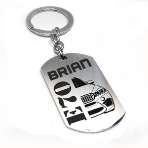 May include: Silver keychain with a black and white silhouette of a car and the text "BRIAN 2021" engraved on it.