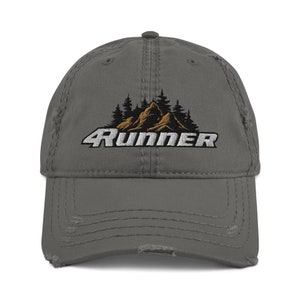 Puede incluir: Una gorra de béisbol gris desgastada con un logotipo bordado en blanco que dice "4Runner" y una escena de montaña bordada en marrón.
