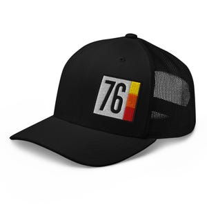 Könnte beinhalten: Schwarze Trucker-Cap mit Mesh-Rückseite und gebogenem Schirm. Auf der Vorderseite befindet sich ein rechteckiger Aufnäher mit der weißen Zahl "76", einem weißen Rand und einem gelb, orange und roten Farbblock.