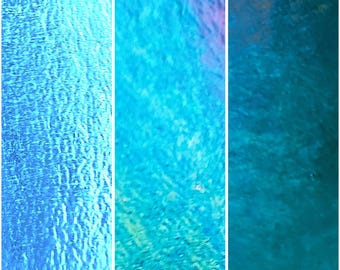 May include: A triptych of abstract images with a water-like texture. The panels feature shades of blue, ranging from light turquoise to deep teal. The textures vary, with some panels appearing smooth and others showing a rippled effect, creating a sense of depth.