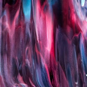 May include: Abstract glass art with flowing patterns in shades of red, purple, and blue. The colors blend and swirl, creating a dynamic and textured appearance. The artwork has a glossy finish and a unique, artistic aesthetic.