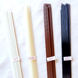 May include: Four bundles of floral wire in white, cream, brown, and black. Each bundle has a label with a number written in red ink. The wires are arranged vertically against a white background.