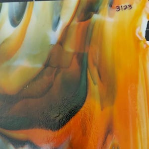 May include: A sheet of art glass featuring a marbled pattern of vibrant orange, deep green, and creamy white swirls. The surface is smooth and glossy with a semi-translucent quality. The number 3123 is written in black ink in the upper right corner.