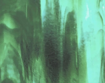 May include: A sheet of translucent glass featuring a marbled pattern with varying shades of mint green, emerald, and forest green. The surface displays organic, flowing streaks and swirls of color that create a semi-opaque, layered visual effect.