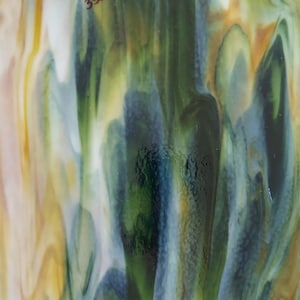 May include: Abstract art featuring a blend of green, blue, and yellow colors in a swirling, fluid pattern. The colors are vibrant and create a sense of movement.