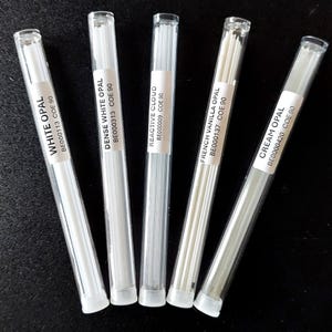 May include: Five clear plastic tubes containing glass rods, each labeled with a different opal name: White, Dense White, Reactive Cloud, French Vanilla, and Cream. The labels also include a product code and COE 90.