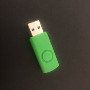 May include: A green USB flash drive with a circular button on the side.