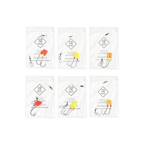 May include: Six sealed clear plastic bags, each containing fishing rigs. Each bag has a white label with the text "12 RIGS" in a black diamond. The rigs feature hooks, swivels, and colorful floats in red, yellow, and orange.