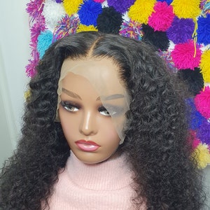 May include: A black curly human hair wig on a mannequin head. The wig is styled in loose curls and has a lace front.